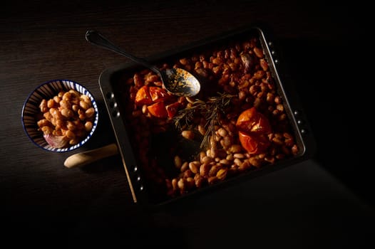 Delicious baked beans with roasted tomatoes and fresh rosemary showcased in a rustic, contrasting setting. Perfect for food concepts, home cooking, and comfort meals imagery.