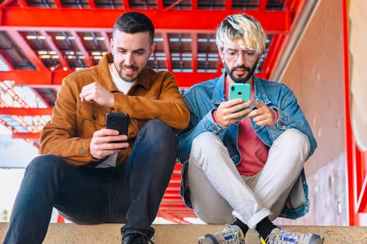 Two young Caucasian male friends sitting outside, focused on their smartphones. Vibrant urban environment with casual style, representing digital lifestyle and everyday interaction.