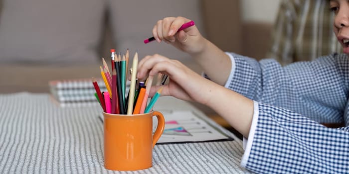 A vibrant scene showcasing a teenage girl with Down syndrome as she picks colorful pencils from a cup, ready to express her creativity through art in a cozy home setting.