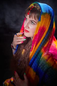 A mature woman showcases her beauty in a vibrant sari while posing in an artistic Indian themed setting.