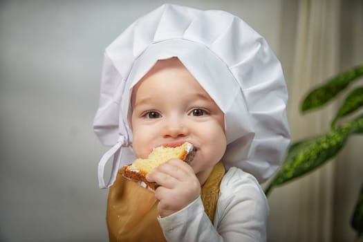 A curious boy wearing a chef's hat gazes thoughtfully while her photo is taken in a warm and inviting studio space.
