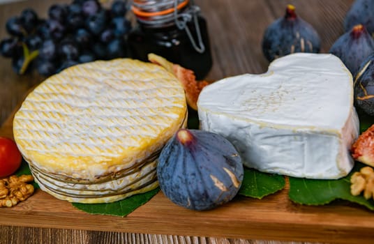 Selection of French cheeses from Normandy, AOP, Livarot, Neufchatel, Pont l'eveque, Rye bread, figs, walnuts, grapes, elderberry gelee. High quality photo