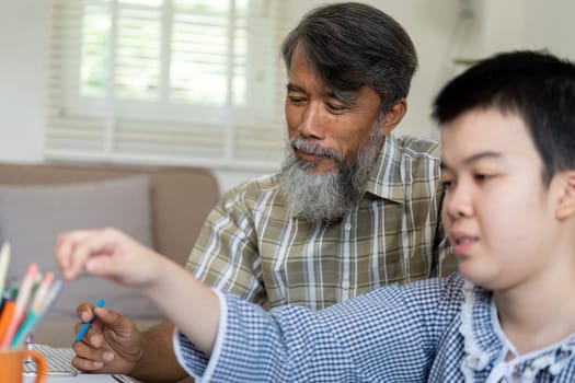 In a nurturing environment, a teenage girl with Down syndrome is deeply engaged in her drawing, with her grandfather providing guidance and encouragement during their art session.
