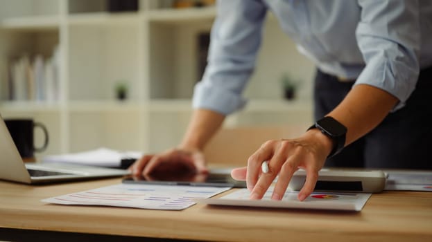 Close up of businessperson reviewing statistics and graphs at office desk.