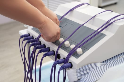 High angle of crop anonymous doctor preparing machine for anti cellulite massage