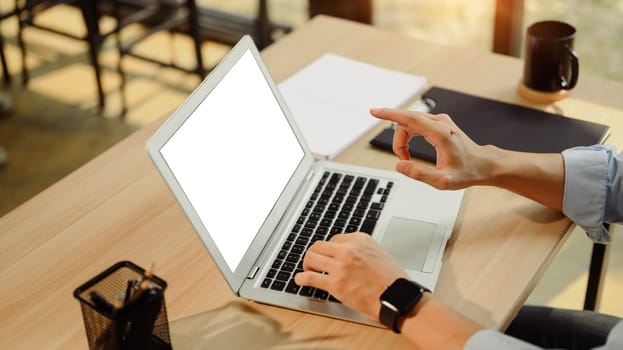 Close up of businessman typing and pointing at a laptop with a white screen.