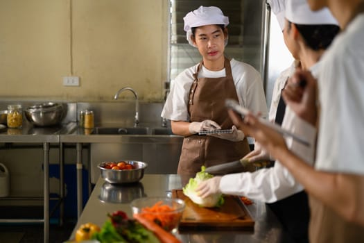 Student chef attentively observing food preparation during cooking class.