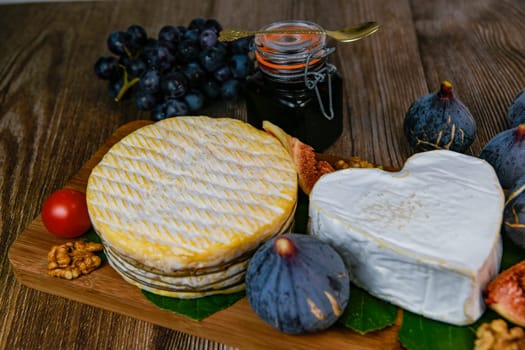 Selection of French cheeses from Normandy, AOP, Livarot, Neufchatel, Pont l'eveque, Rye bread, figs, walnuts, grapes, elderberry gelee. High quality photo