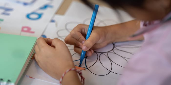 A young girl concentrates on creating detailed designs, showcasing her artistic skills in a vibrant classroom setting.