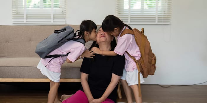 Two girls affectionately kiss their mother after returning from school, showcasing the bond and love within the family. This moment captures the joy of reunion.