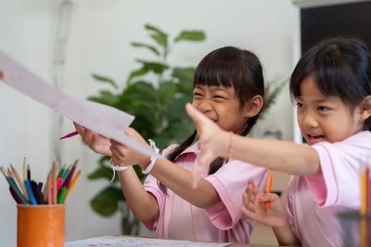 Two young girls joyfully exchange their drawings, showcasing creativity and friendship in a vibrant school environment filled with art supplies.