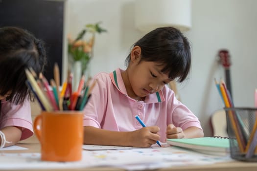 A young girl focuses intently on her artwork, demonstrating dedication and concentration in a classroom environment filled with creativity.