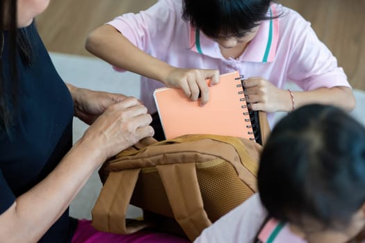 Two children happily pack their school bags with the help of a loving adult, showcasing the excitement of starting a new school year.
