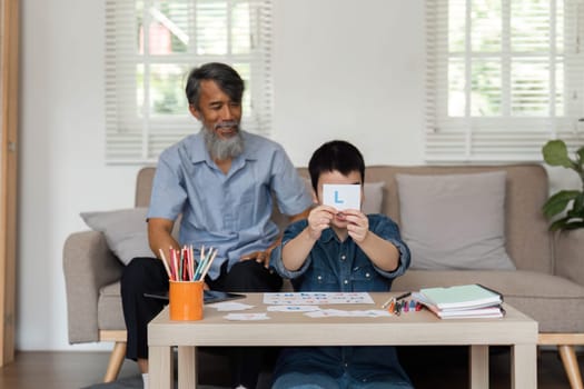 During a cozy home session, a grandfather assists his grandson in recognizing letters, creating a supportive learning atmosphere filled with love and encouragement.