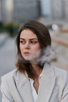 Thoughtful young woman in light gray blazer with smoky effect, standing outdoors in urban city background, conveying emotional business and psychological challenges.