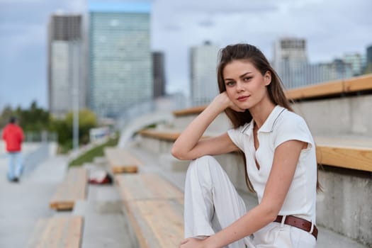 A confident business woman in light clothing sits thoughtfully on a bench, surrounded by an urban backdrop, reflecting a modern and professional vibe perfect for business themes.
