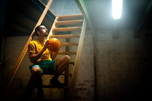A basketball player is lost in thought within a moody atmosphere, capturing a moment full of reflection and passion