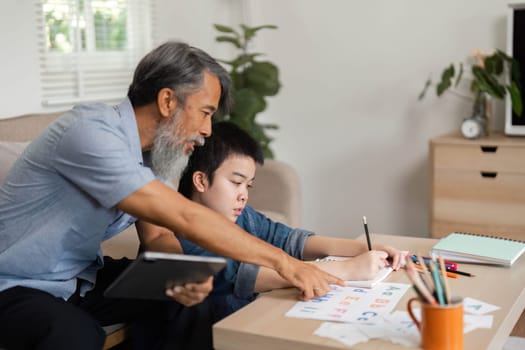 A grandfather shares quality time with his grandson, using interactive learning tools to teach letters and foster a love for learning in a warm home setting.