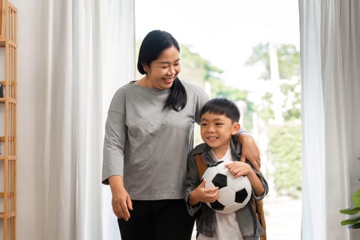 A mother and her son walk together after soccer practice, sharing smiles and laughter, highlighting their strong family bond.