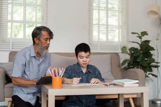 A grandfather attentively watches as his grandchild draws, fostering creativity and learning in a nurturing environment.