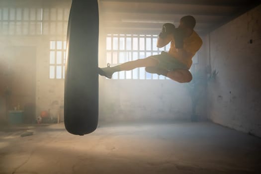 A skilled athlete delivers a powerful high kick on a punching bag in a vibrant training space where fitness thrives