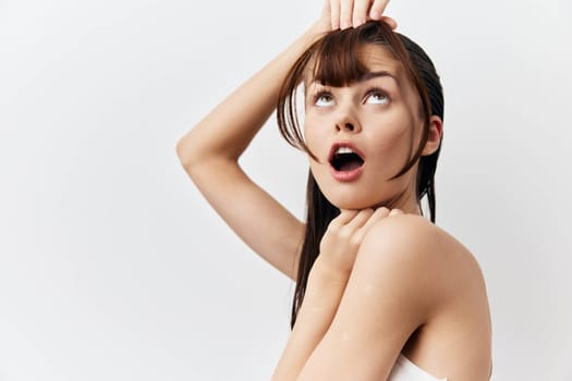 This image captures a surprised young woman with long brown hair and bangs, showcasing a curious expression against a clean white backdrop Her wide eyes and open mouth reflect astonishment