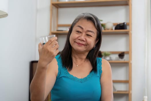 An elderly woman admires a skincare jar in her hand, contemplating her beauty regimen and the importance of self-care in her life.