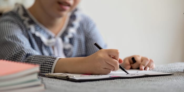 The girl is deeply engaged in her drawing, showcasing her artistic skills and the joy of creative expression.