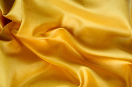 Top view of dark yellow satin fabric with a glossy finish. Suitable for design and wallpaper background.