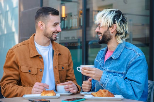 Two friends share a joyful moment at an outdoor cafe, smiling while drinking coffee and eating pastries. Casual conversation and relaxed vibe in an urban setting with natural light and glass walls.