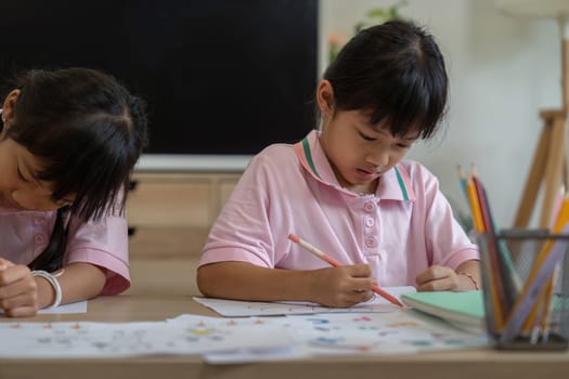 Two sisters concentrate on their coloring tasks, showcasing their creativity and focus. This moment highlights the joy of learning through artistic activities.