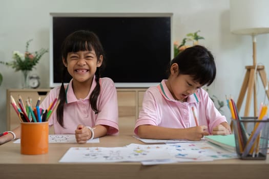 Two sisters enjoy a coloring session, one excitedly showing her artwork while the other focuses on her own. This moment reflects the beauty of collaboration and artistic expression.