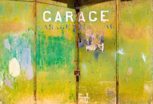 Old rusty green metal garage gate with a lock on it