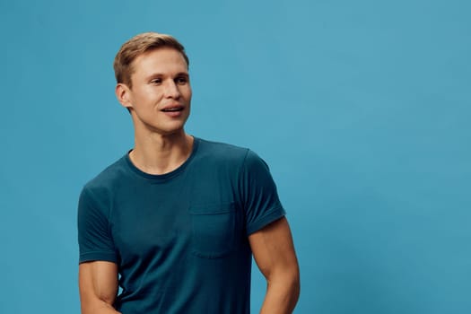 smiling young caucasian man wear teal t-shirt look away thoughtful optimistic casual style isolated on solid blue background digital nomad remote work lifestyle concept
