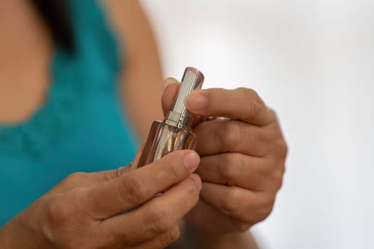 An elderly woman holds a bottle of perfume, symbolizing her dedication to beauty and self-care as part of her daily routine.