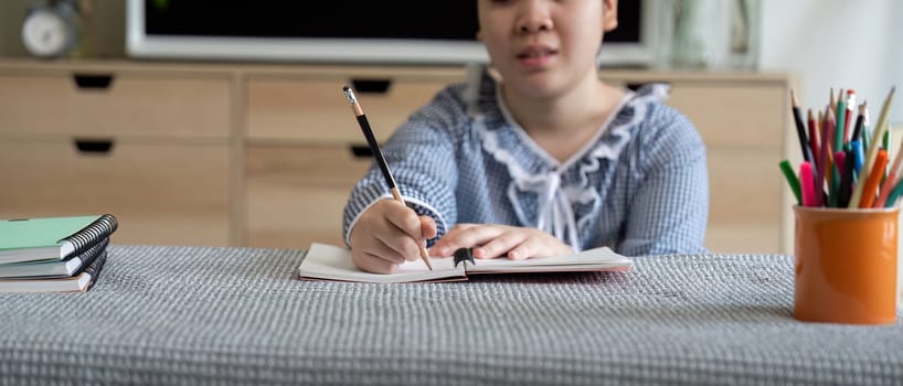 The girl is deeply focused on her writing task, showcasing her commitment to learning and creativity in a comfortable setting.