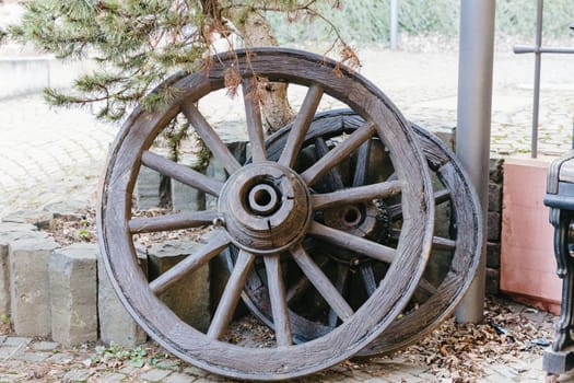 Beautiful view of two old wooden wheels with metal rim from a cart, which stands outside the historical museum in an old castle on a spring day, side view close-up. Concept of historical landmarks, time of travel and tourism.