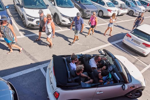 Crete.Greece - april 23, 2025: A stylish convertible with four passengers moves through scenic roads. The carefree atmosphere and the bond between friends create a vibrant moment of travel adventure