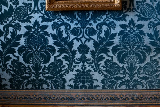 Blue velvet wallpaper and gold frames with paintings in castle