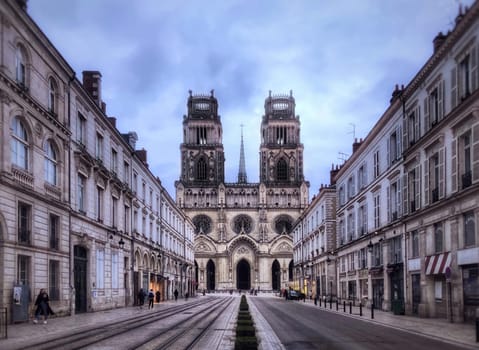 Orleans, France - May 25, 2024: The Cathedral church of Orleans , picturing its facade and the street with buildings