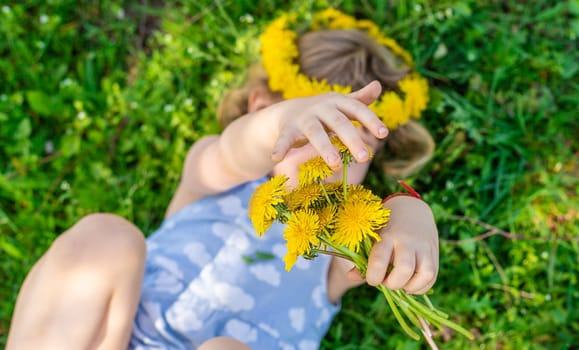 Child in the garden with a bouquet of dandelions. Selective focus. Kid.