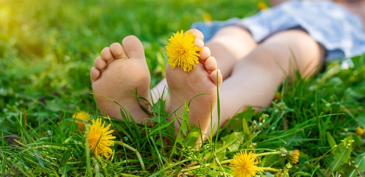 child feet in a garden with dandelions. Selective focus. kid,