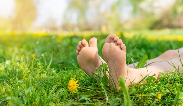 child feet in a garden with dandelions. Selective focus. kid,