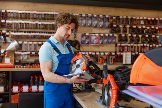 Closeup workman holding circular saw in hands choosing new electric tool for work. Construction worker purchasing at hardware store