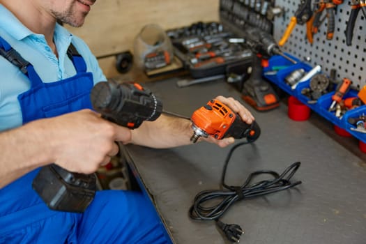 Repairman fixing electrical angle grinder working with screwdriver at workshop. Repair shop for broken power tools