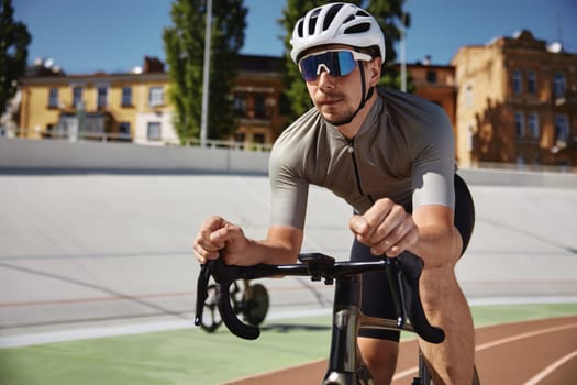 Bicyclist holding hands on steering wheel driving bike. Sportsman practicing alone on velodrome enjoying extreme speed riding