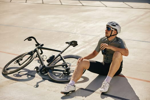 Sportsman with water bottle resting enjoying refreshing time during cycling training on open road sprint track