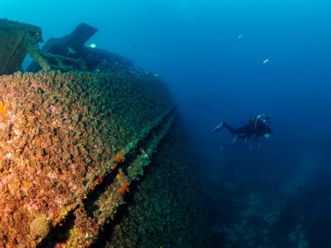 unrecognizable scuba diver diving into the blue ocean near of a wreck, concept of underwater adventure and active leisure lifestyle, copyspace for text