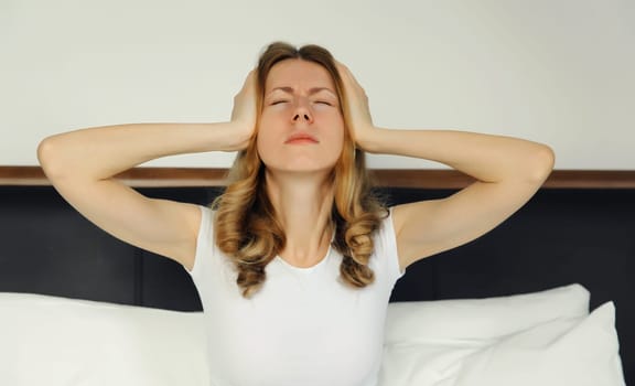 Exhausted tired woman touching head, suffering from headache, stress, fatigue, temples pain, migraine, loud noise, tension lying on the bed in bedroom at home