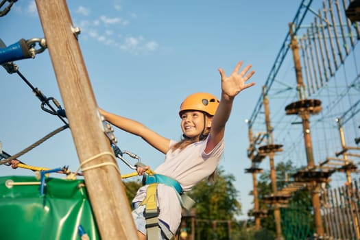 Happy little girl child having fun time at open air rope park during summer vacation. Sport and extreme hobby activity for children